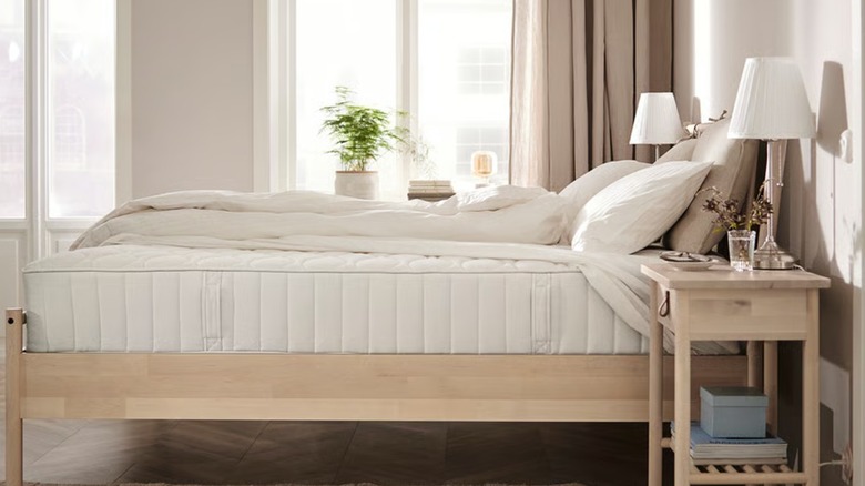 A thick white mattress on a wood frame in a bedroom