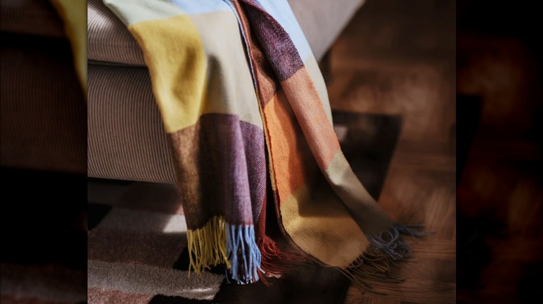 A checkered throw blanket in earthy tones on a tan couch