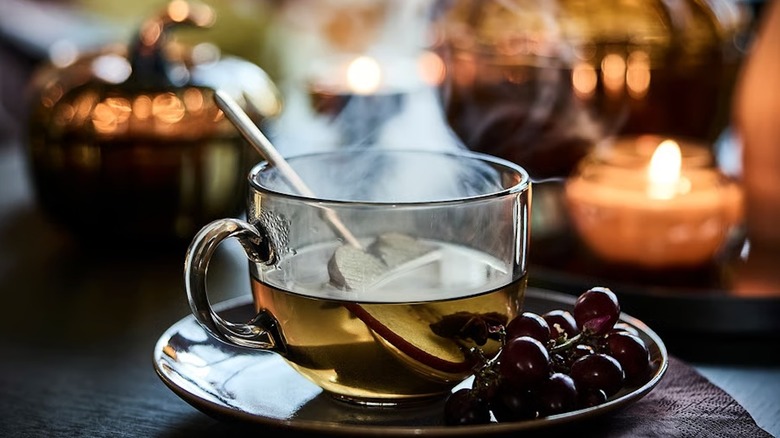 HÖSTAGILLE Mug in light brown with a warm drink on the table with candles and pumpkin accents