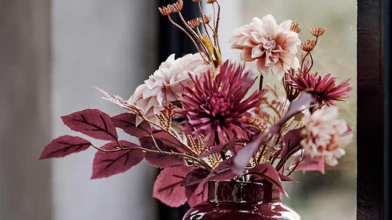 SMYCKA Artificial bouquet in pinks and maroons in a deep maroon vase on a windowsill