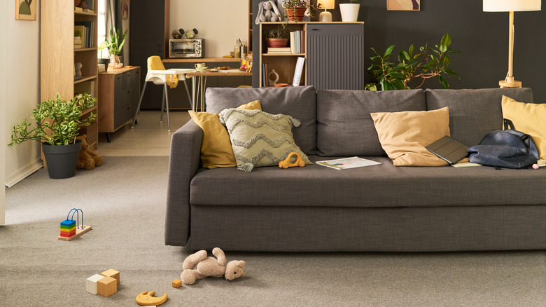 A living room cluttered with toys on the floor and sofa