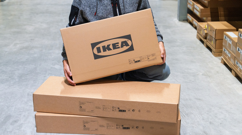 A person holding an IKEA box in a warehouse