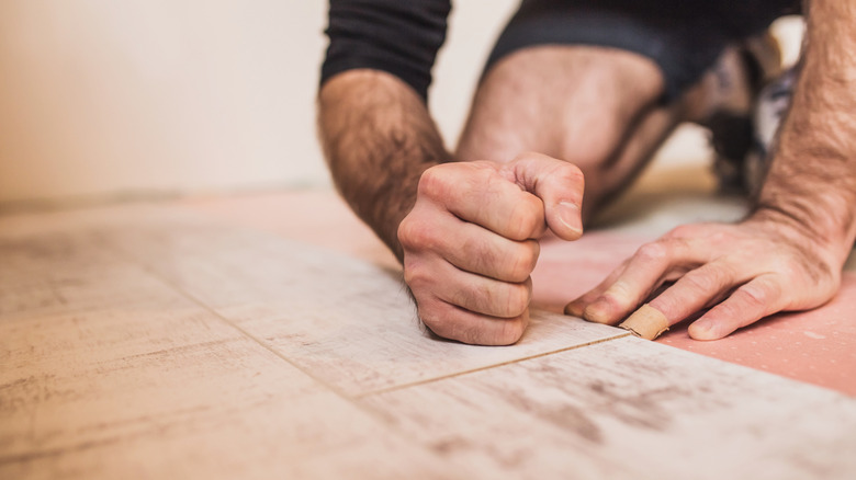 Installer pounding flooring together by hand
