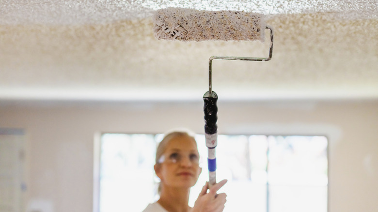 A woman painting a ceiling with a roller