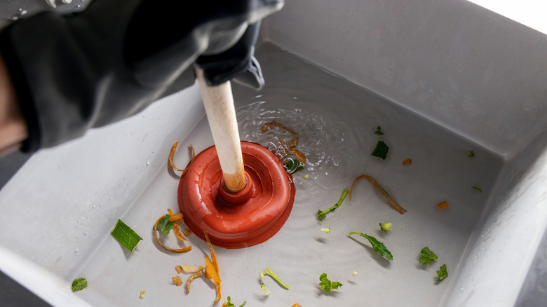 Attempting to unclog a drain with a plunger