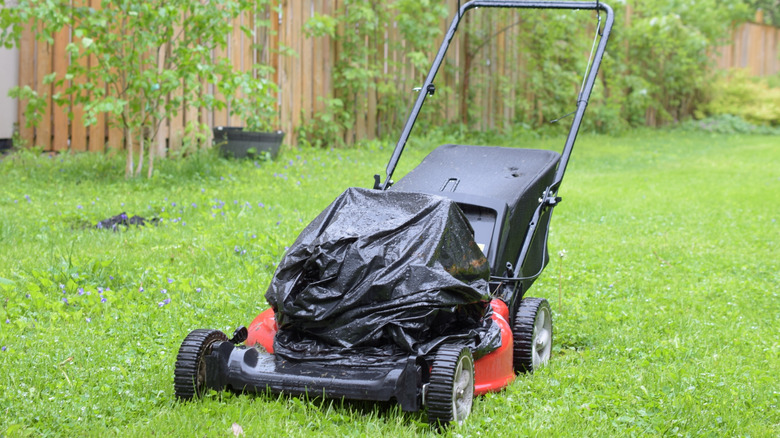 Lawn mower covered in a trash bag with raindrops on it