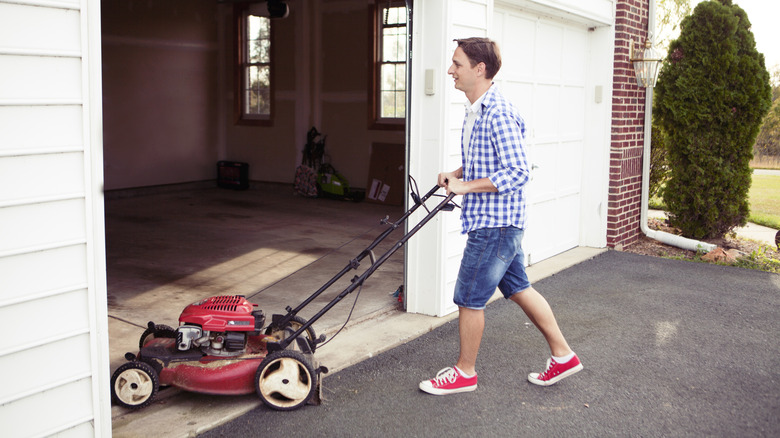 Person putting lawn mower away in garage