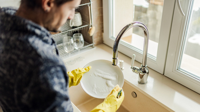 Person washing dishes with soap.