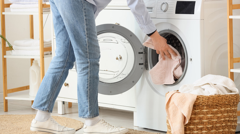 A person loading towels into the washing machine.