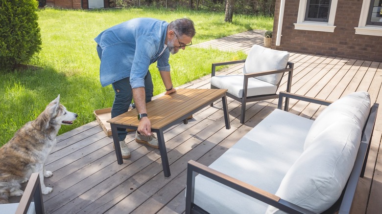 Man setting up a new patio furniture set on his back deck
