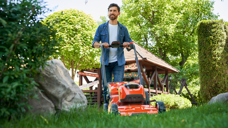 Smiling man mowing lawn