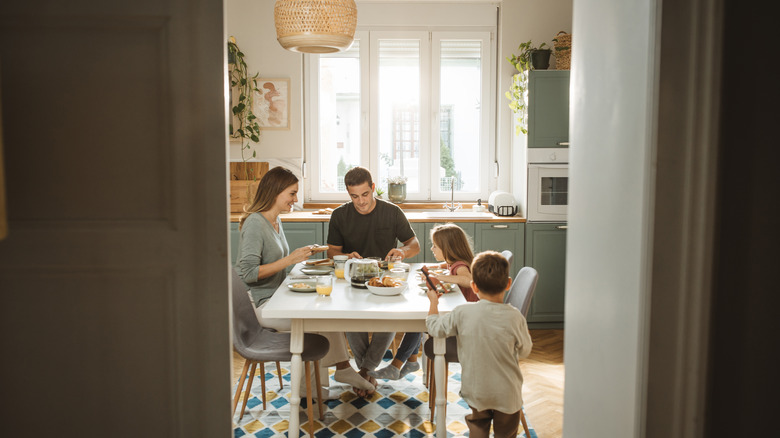 a young family eats breakfast in their kitchen