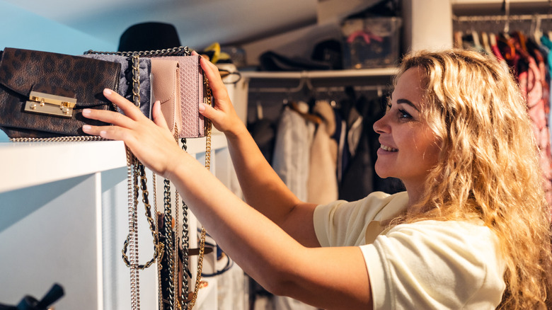 A person organizing handbags in a closet