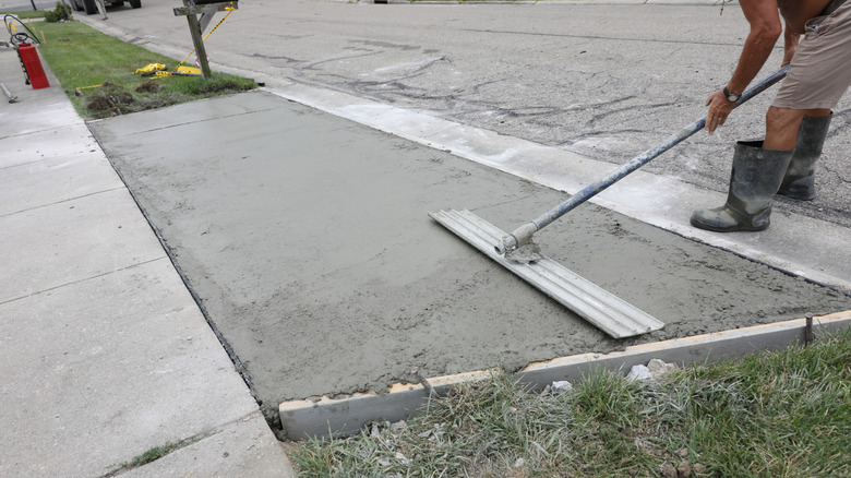 Worker smoothing concrete on the apron of a driveway