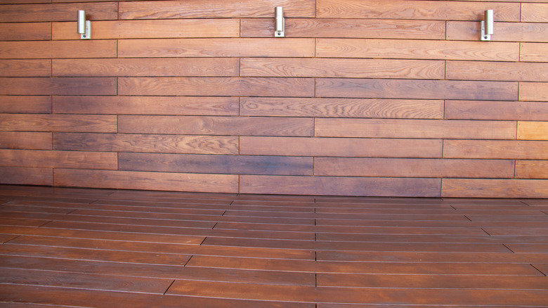 A deck and wall made of thermally modified wood, in a natural dark brown tone.