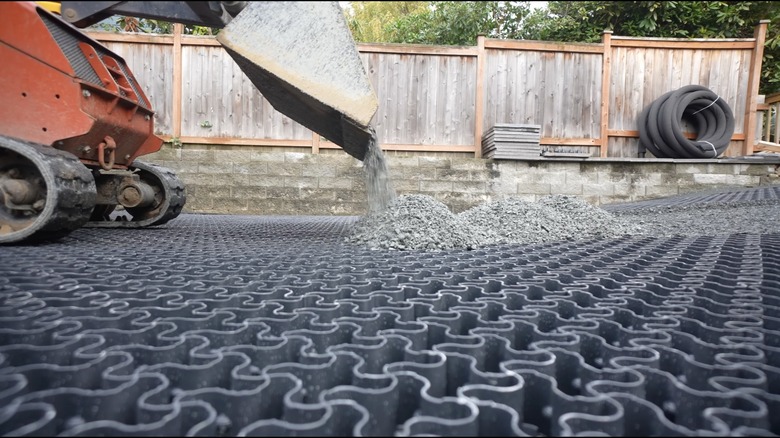 Person installing EasyPave Gravel & Grass Driveway Grid and filling it with gravel