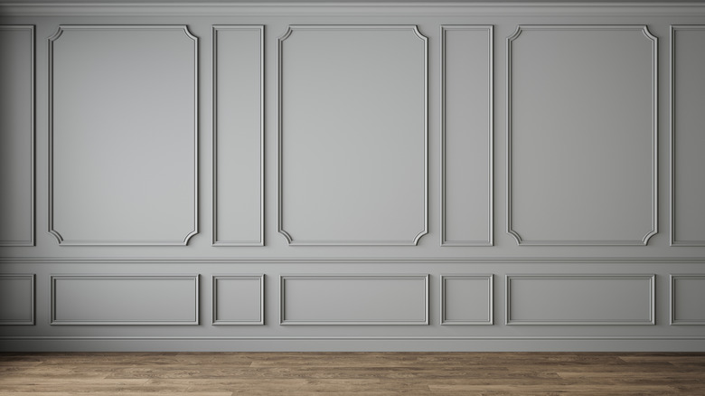 Table with a potted plant in front of a green wall with decorative moulding