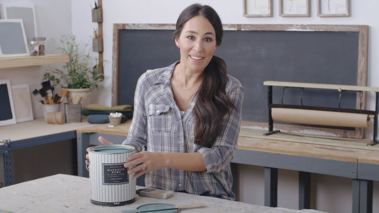 Joanna Gaines holding a paint can on a work table