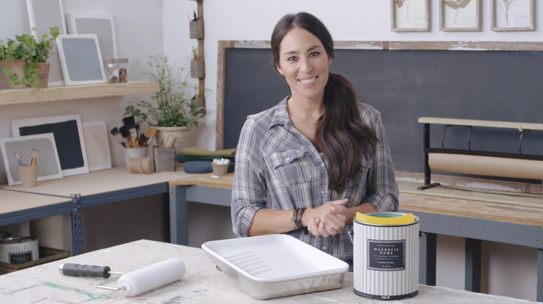 Joanna Gaines stands behind a table with paint supplies
