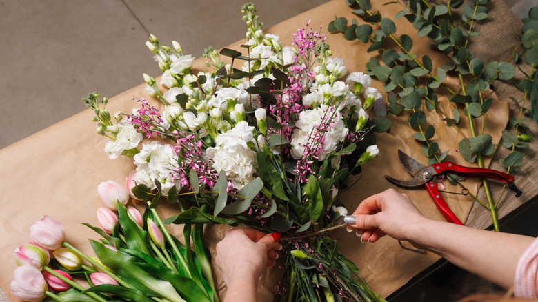 Person creating a bouquet of cut flowers and leaves