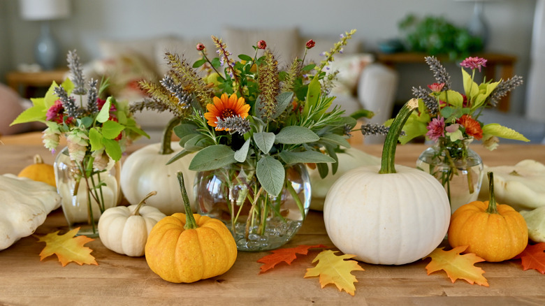 A centerpiece of seasonal fresh flowers and miniature pumpkins