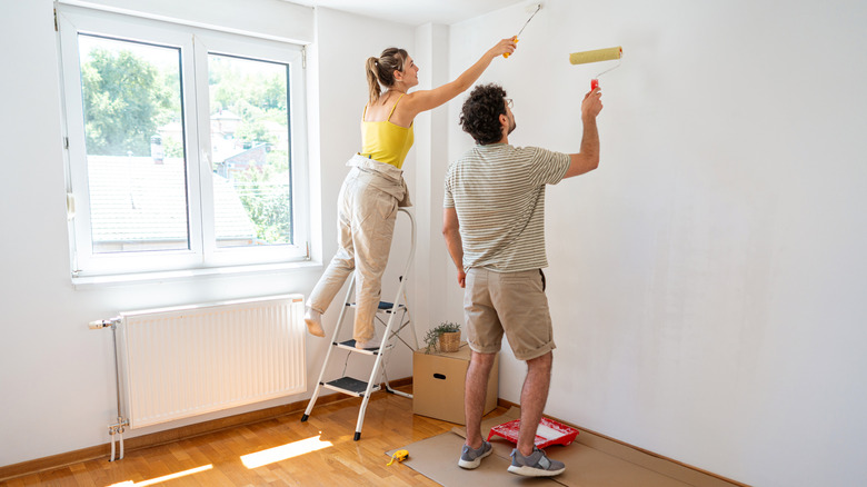 Couple painting walls in a living room