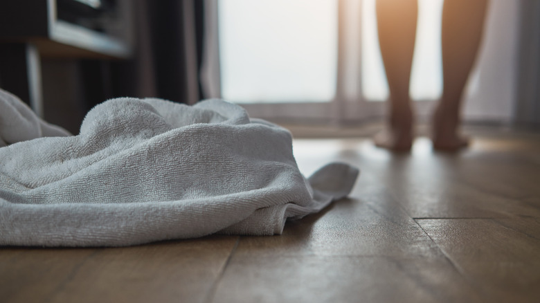 white towels on bathroom floor with blurred legs in the background