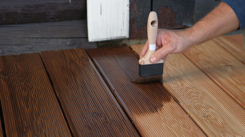 Person painting wood deck