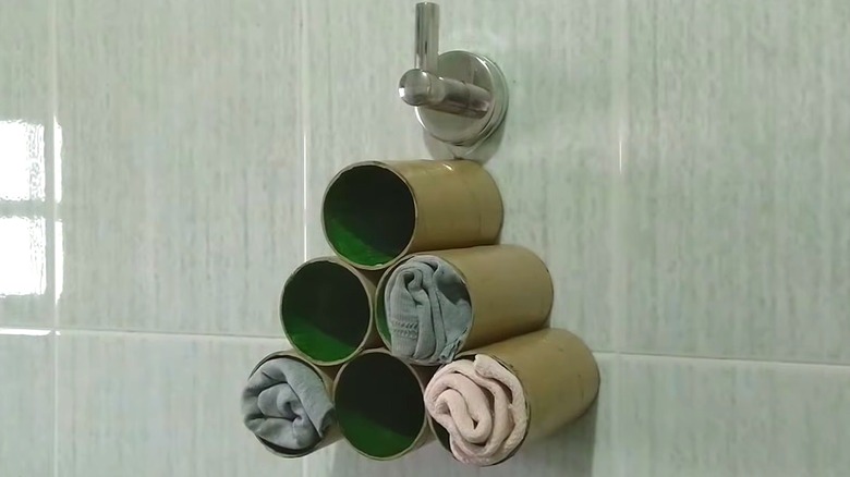Hanging toilet paper tube DIY with spare cleaning rags hanging from hook in tiled bathroom