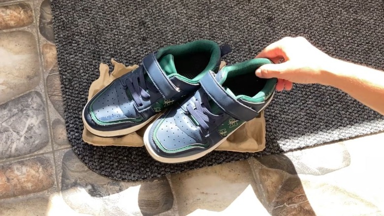 Person putting dirty shoes on empty egg carton to keep floors clean.