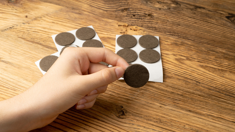 Person peeling away furniture felt pads