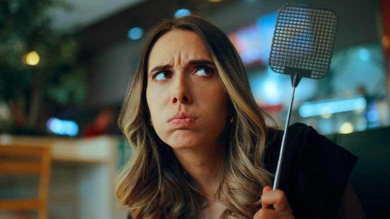 Annoyed woman holding fly swatter