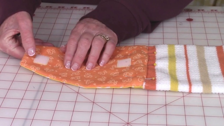 Person attaching hook and loop fasteners to kitchen dish towel