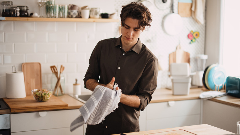 Person drying hands with a kitchen towel