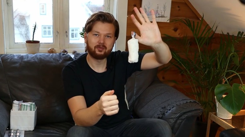 A man holds up a folded dish towel