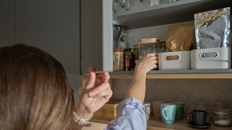 Person reaching into pantry to organize items in a kitchen