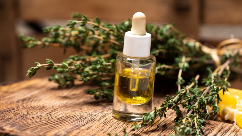Thyme oil in a bottle with fresh sprigs of thyme