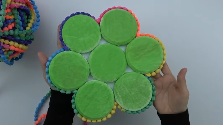 Woman holding trivet made from jar lids and fabric