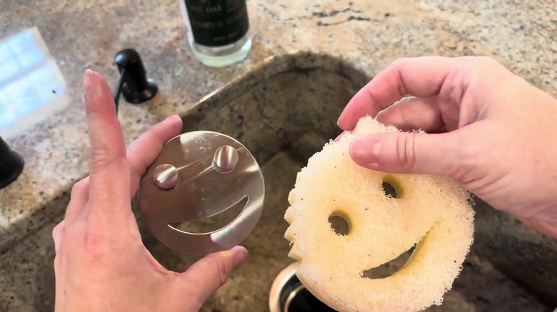 Woman holding a scrub daddy and stainless steel holder