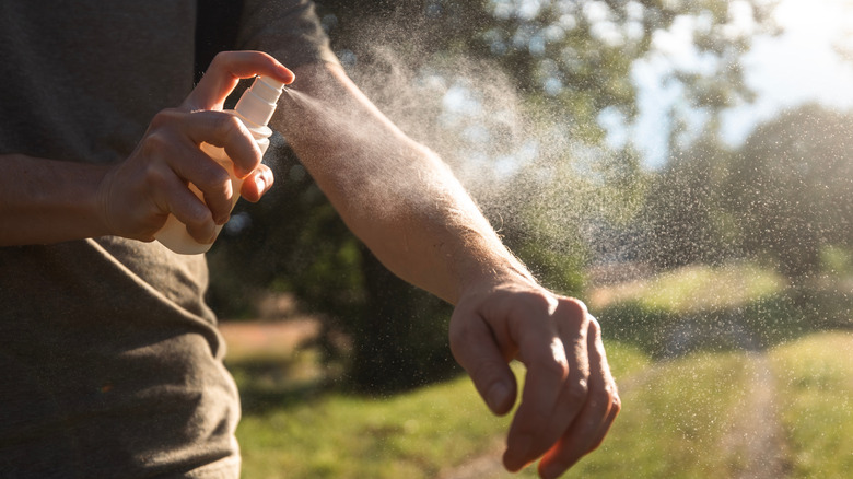 close up of man spraying insect repellent on his arm