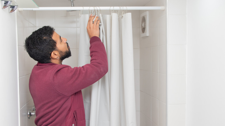 Man taking down old shower curtain