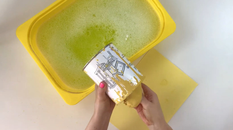 Person cleaning out an old paint can