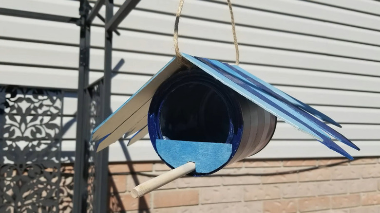 Paint can bird feeder with a wood roof