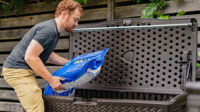 Man storing potting soil in a Suncast deck box