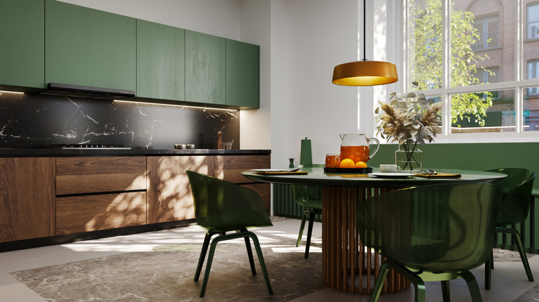 A modern kitchen has dark green and wood cabinets