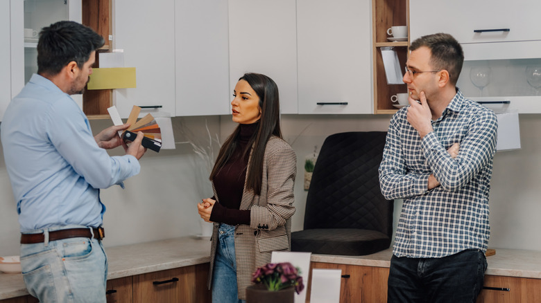 A couple discusses kitchen cabinet colors with a designer