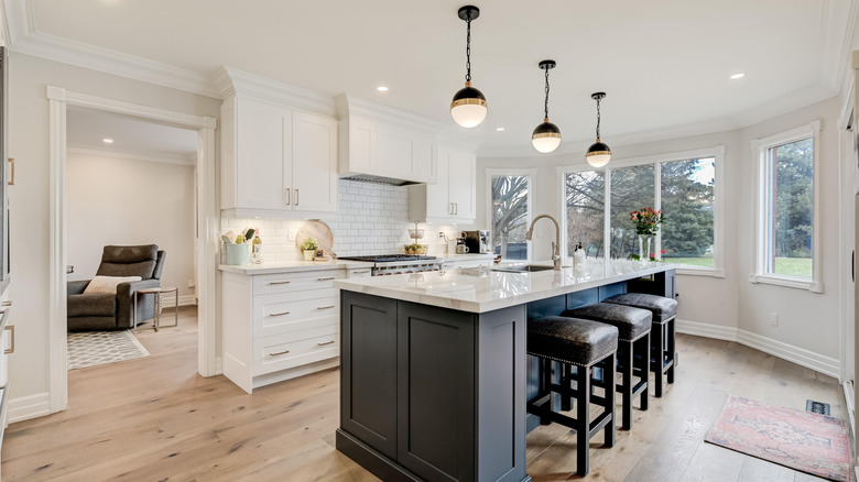 Three pendant lights hang above the island in a large white kitchen