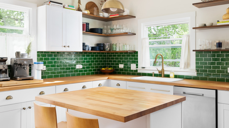 kitchen with butcher block countertops, green tile in background and gold hardware