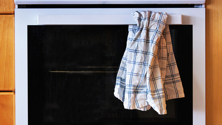 A checked kitchen towel hanging on an oven