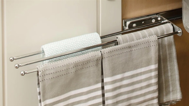 A slide-out towel bar holding towels extended out of under-sink cabinet